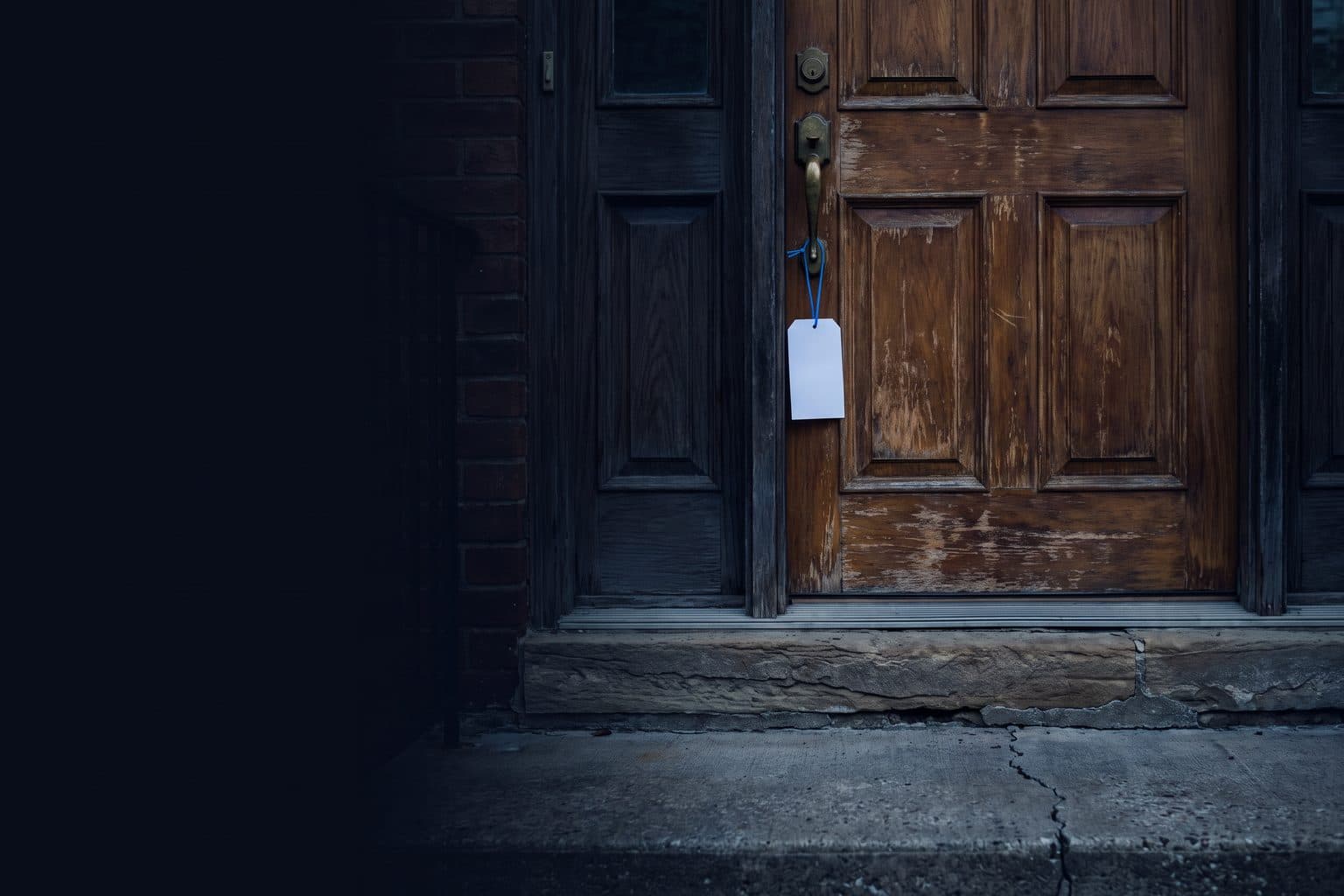 A worn wooden front door on an old house, a blank tag hanging from the handle